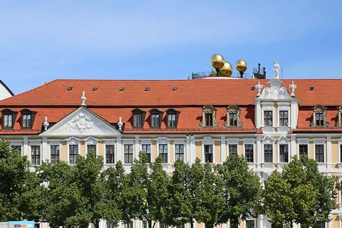 The Landtag building on Domplatz in Magdeburg, seat of the Saxony-Anhalt state parliament, seen from across a tree-lined square, with three gold spheres on the roof