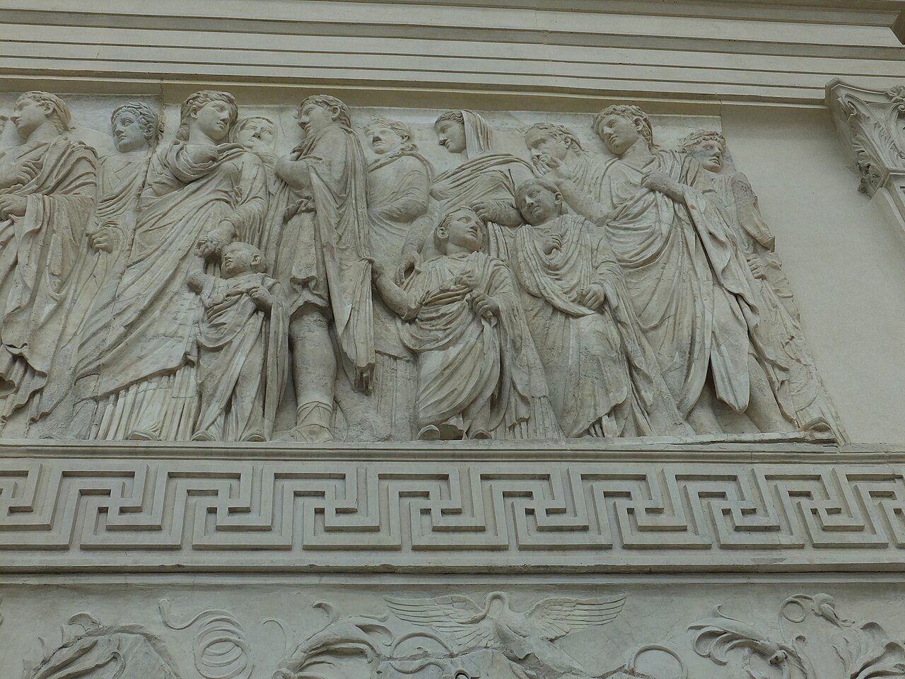 Part of the Ara Pacis processional frieze: robed adults, some with covered heads, walking with small children who hold their clothes