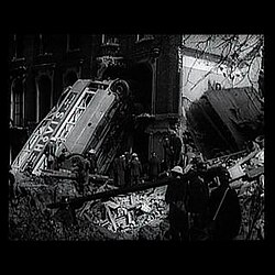 Frame from Britain Can Take It (1940): a bus thrown against a bombed building