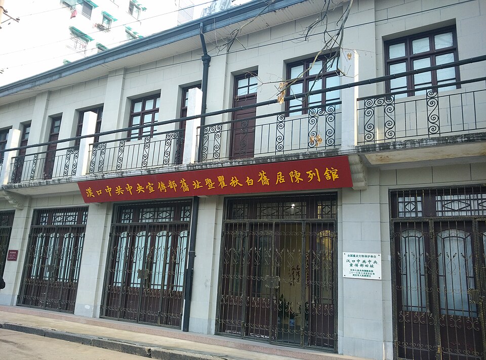 Two-storey building with iron-grille balconies and a red signboard reading 'Hankou CCP Central Propaganda Department former site and Qu Qiubai former residence exhibition hall'