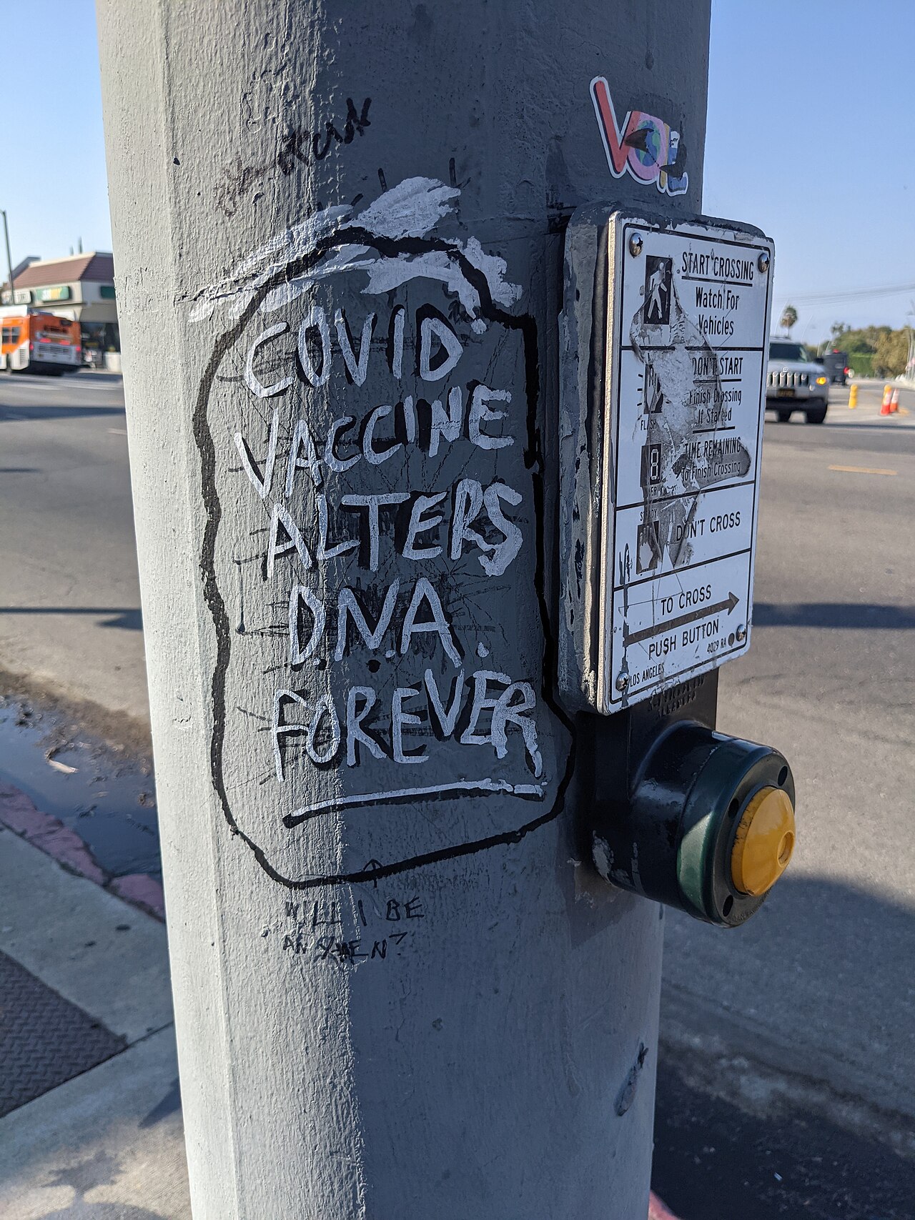Hand-painted "Covid vaccine alters D.N.A. forever" on a crossing pole, Los Angeles, 2021