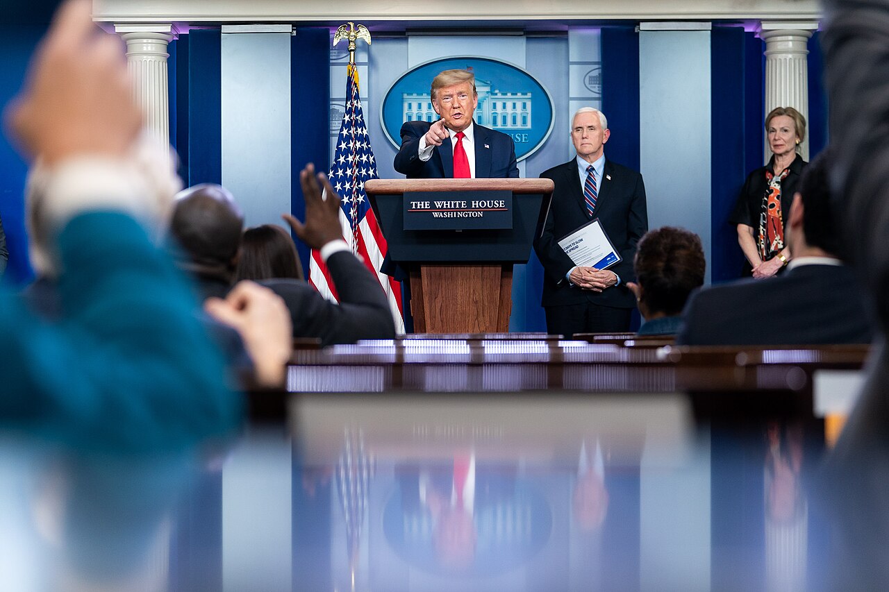 President Trump at a coronavirus briefing, 26 March 2020, with Vice President Pence holding the "15 Days to Slow the Spread" guidance