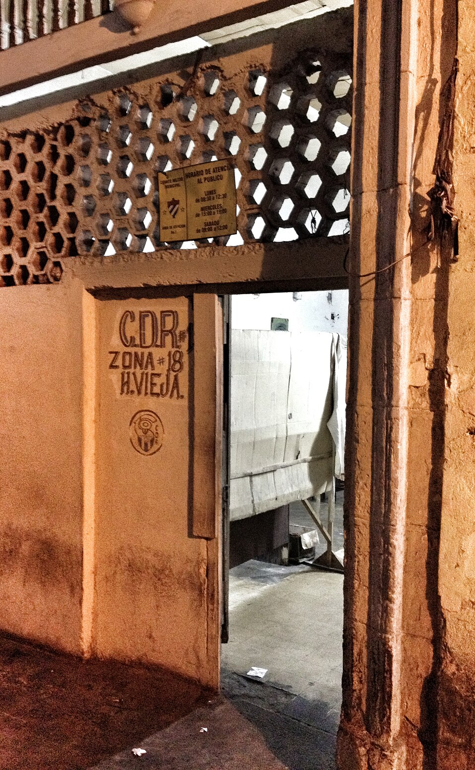 Doorway of a building in Old Havana with hand-painted lettering C.D.R. Zona 18 H. Vieja and a small yellow notice board of opening hours above