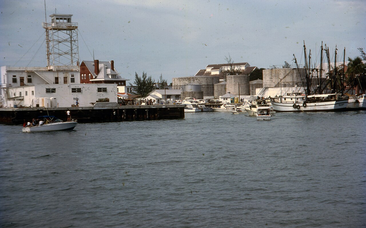 Harbour at Key West with a long pier, small boats and shrimp trawlers moored along it under a grey sky