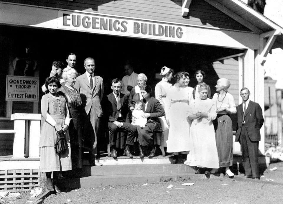 Kansas Free Fair, c. 1925: staff of the Fitter Families contest on the steps of the "Eugenics Building", beside a sign for the Governor's Trophy for the "Fittest Family"