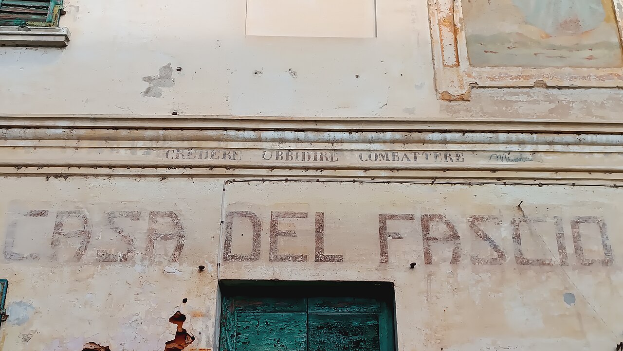 Iscrizione 'Credere Obbedire Combattere' on the Casa del Fascio at Momo, Piedmont, photographed in 2026