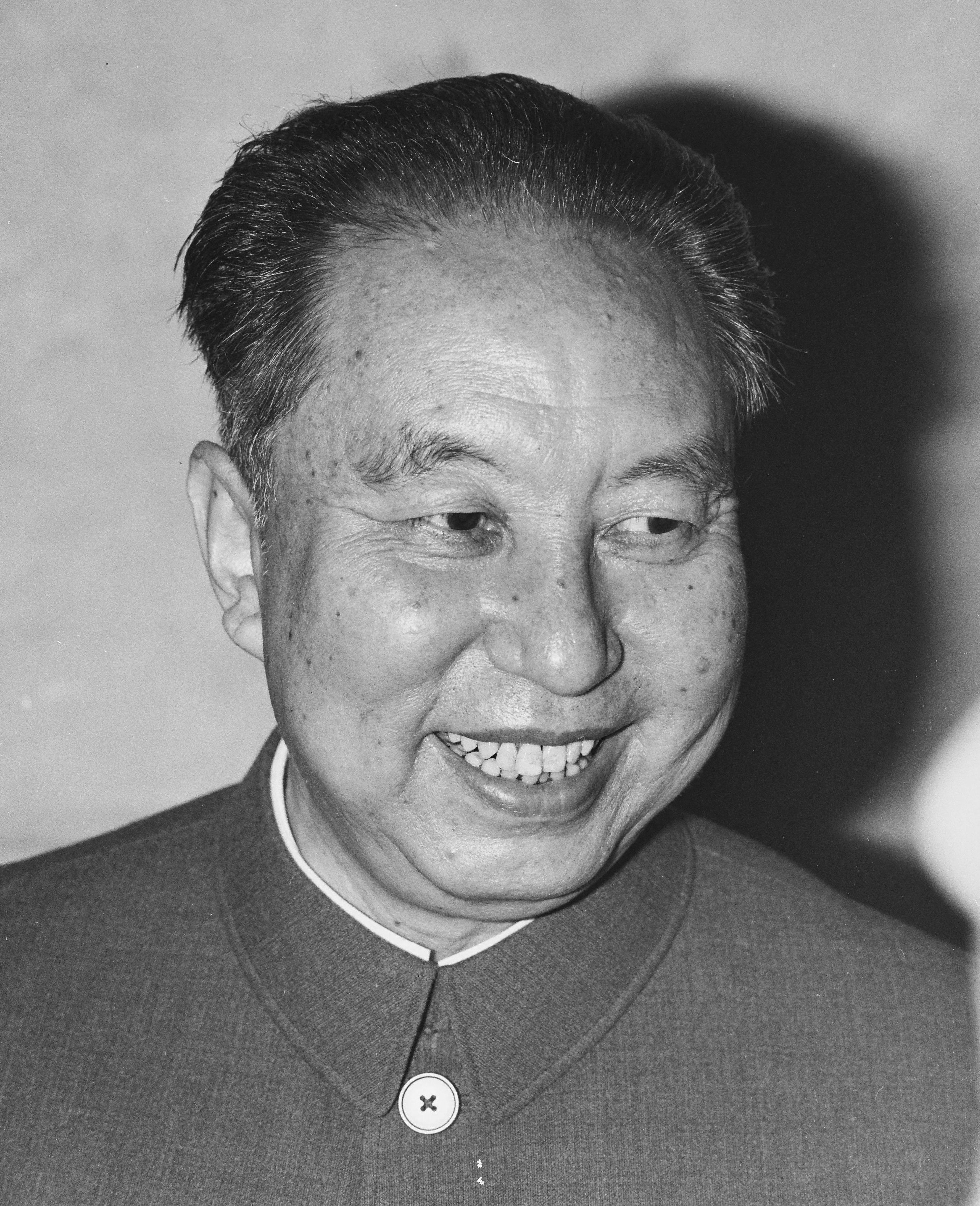 Black-and-white portrait photograph of Hua Guofeng, smiling, in a high-collared tunic