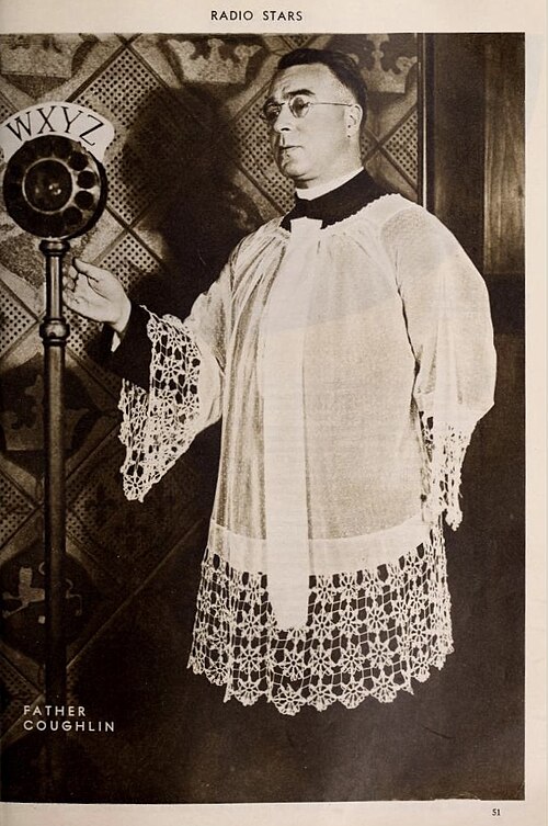 Father Charles Coughlin in clerical vestments standing at a WXYZ radio microphone