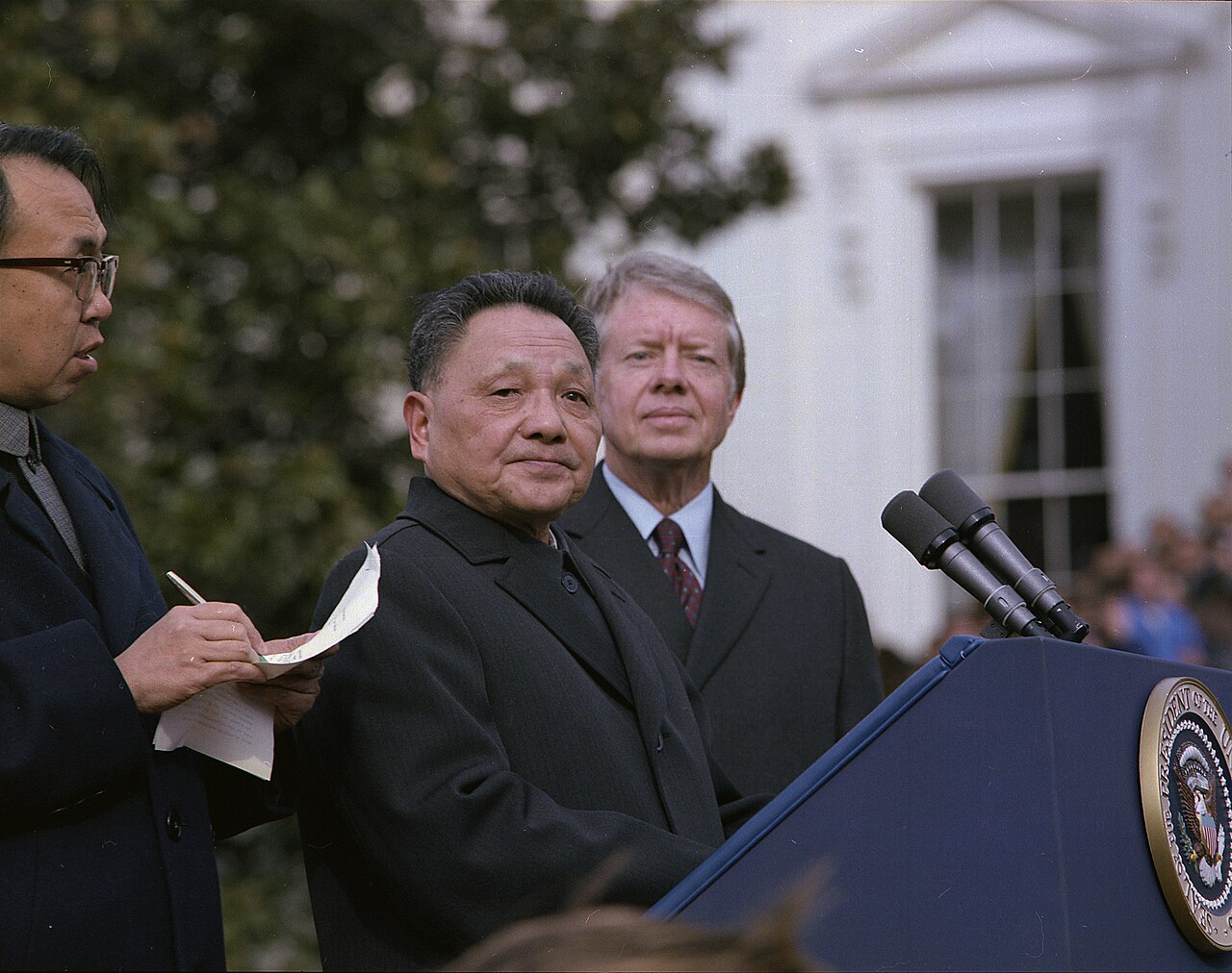 Deng Xiaoping speaking at a lectern on the White House lawn in January 1979 with President Jimmy Carter standing behind him