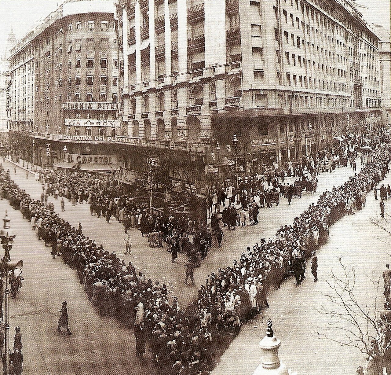 Two long queues of mourners on converging streets in central Buenos Aires, watched from a high window, during Eva Perón's funeral