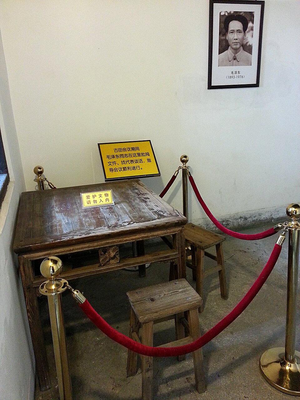 Preserved table and stools at the Gutian Congress site, with a placard about Mao Zedong at the conference and a framed portrait on the wall