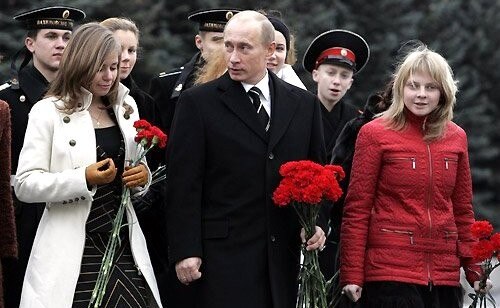 Vladimir Putin walking with young people, some in naval cadet uniform and some holding red carnations, on 4 November 2006