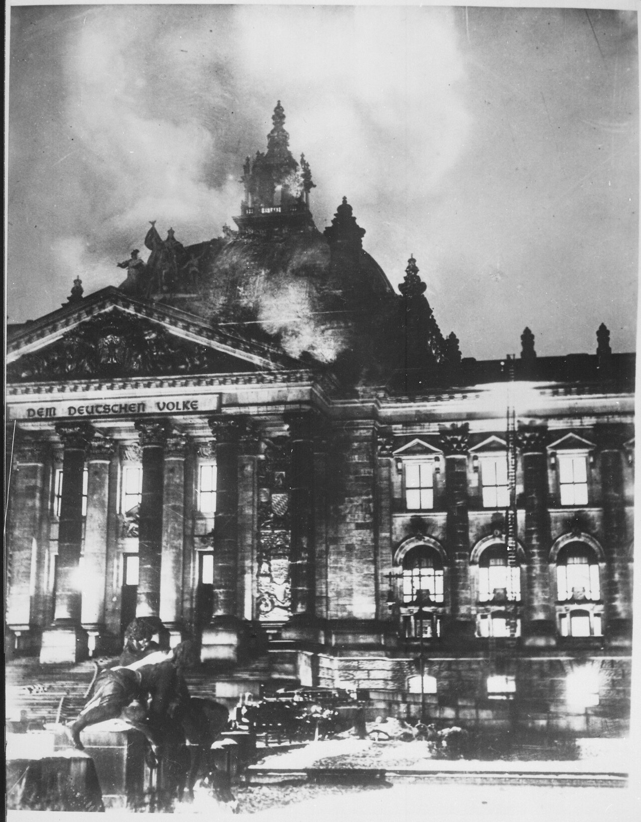 A wartime American caption on a 1933 news photograph of firefighters at the burning Reichstag building: 'This enabled Hitler to seize power under the pretext of protecting the country from the menace to its security.'