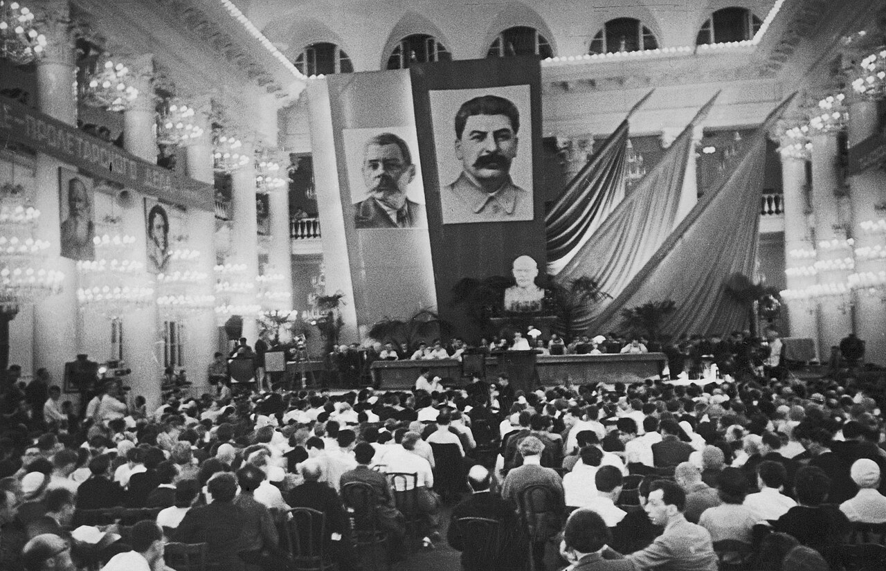 Crowded hall at the 1934 Soviet writers congress in Moscow, with large portraits of Tolstoy, Pushkin, Gorky and Stalin above the presidium table