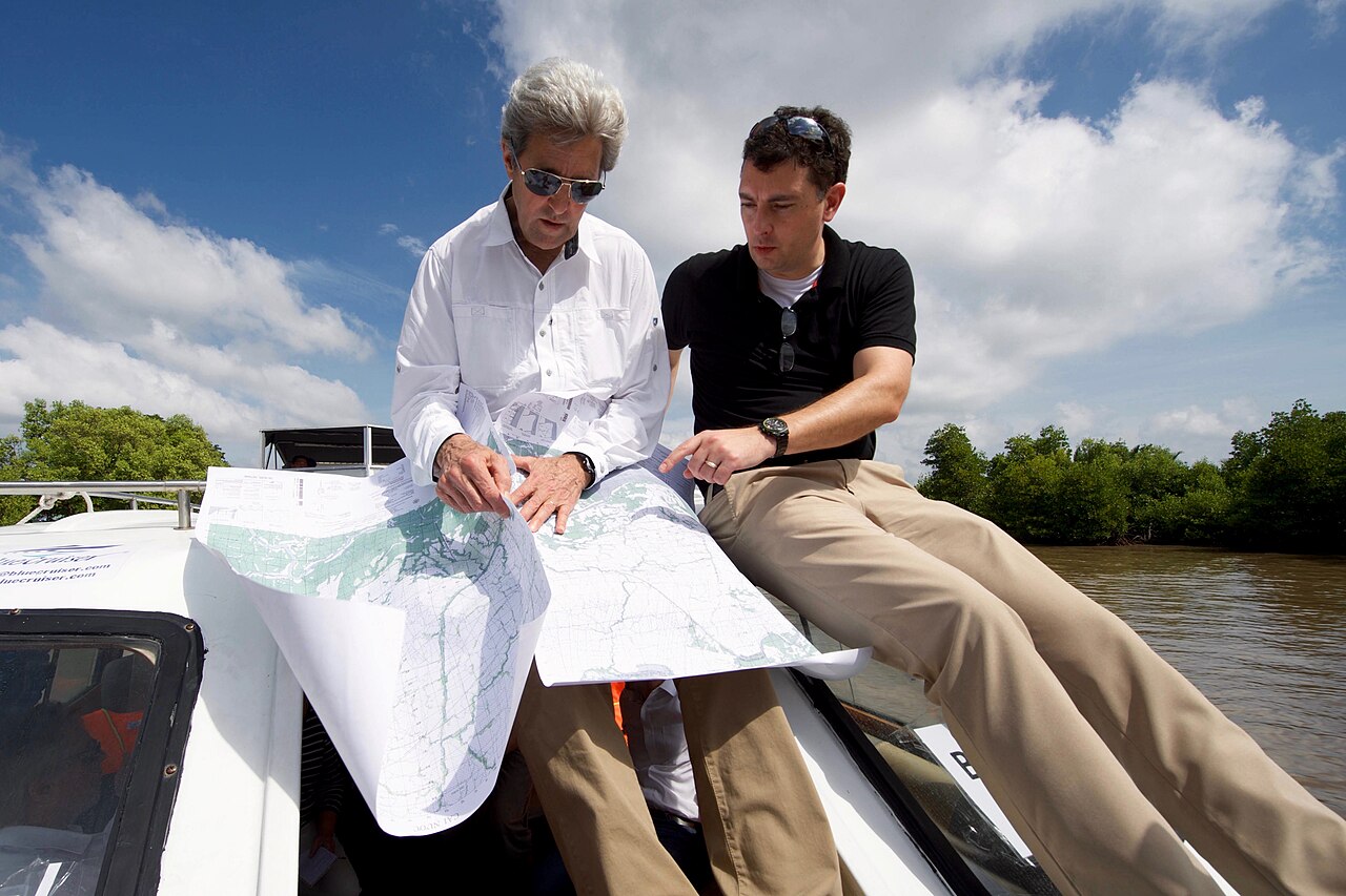 Secretary of State John Kerry and historian Edward Miller look at maps on a boat on the Bay Hap River, Vietnam, January 2017