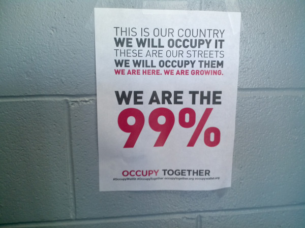 A "We Are the 99%" flyer taped to a wall, headed "This is our country, we will occupy it"