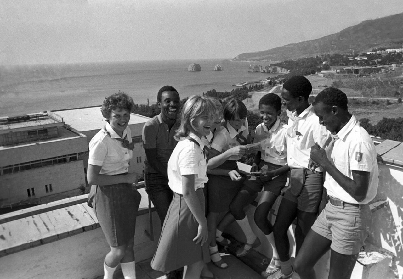 Photograph: Soviet and African children in Pioneer uniforms laughing on a terrace above the sea at Artek
