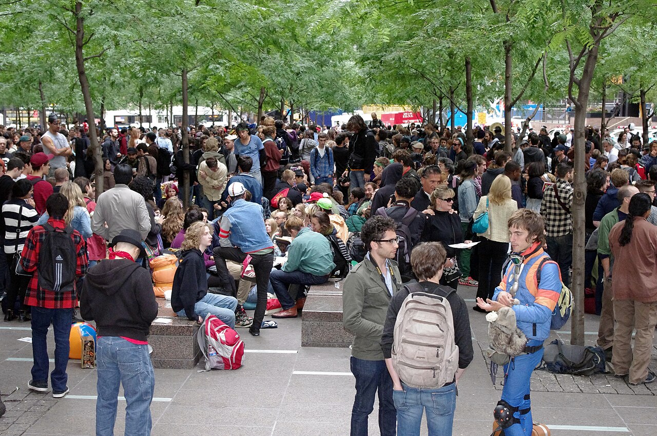 A dense crowd of Occupy Wall Street protesters under the trees of Zuccotti Park