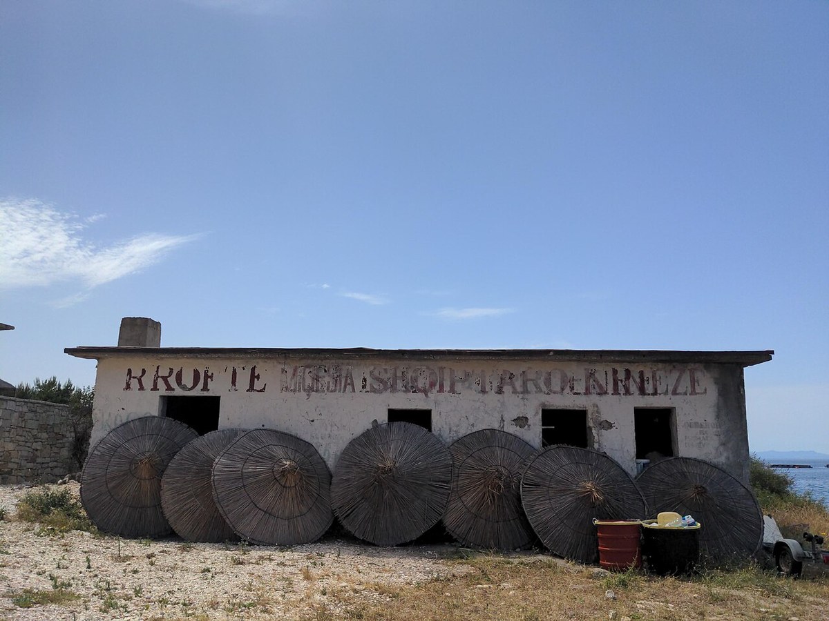 "Rroftë miqësia shqiptaro-kineze": faded slogan on a building at Porto Palermo