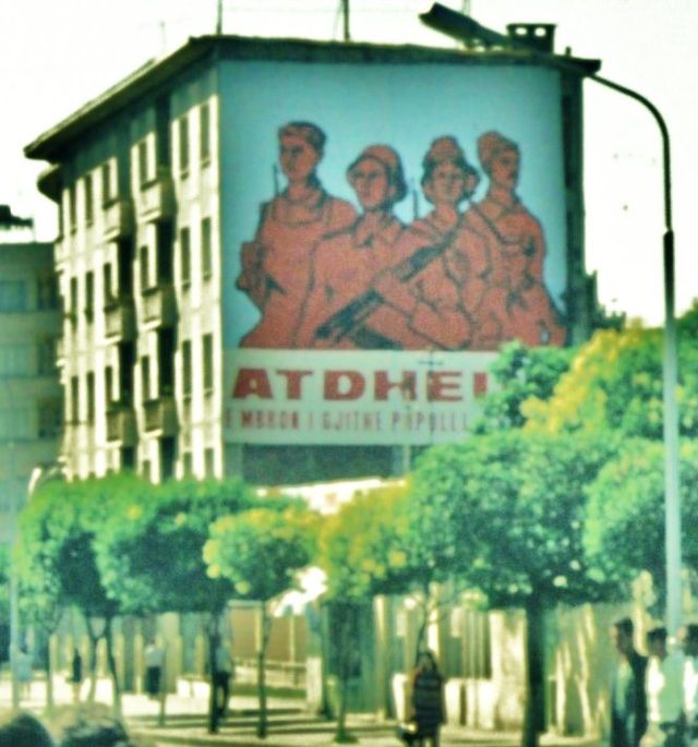"Atdheu e mbron i gjithë populli": mural of armed figures on an apartment block, 1978