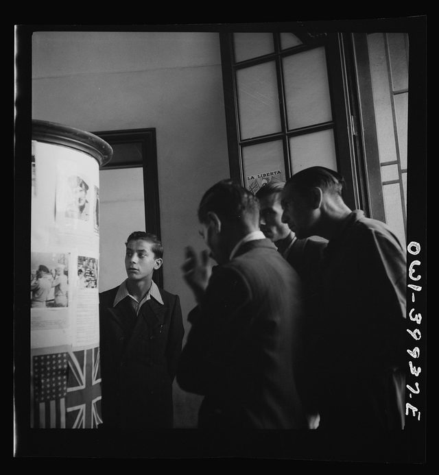 Catania, Sicily: reading Allied news under U.S. and British flags, 1943