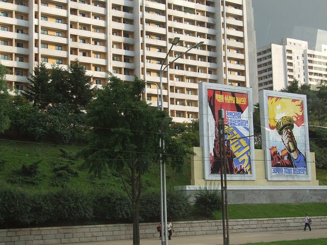 Two billboards: unity around the revolutionary headquarters, and the banner of the Three Revolutions, Pyongyang (photographed 2012)
