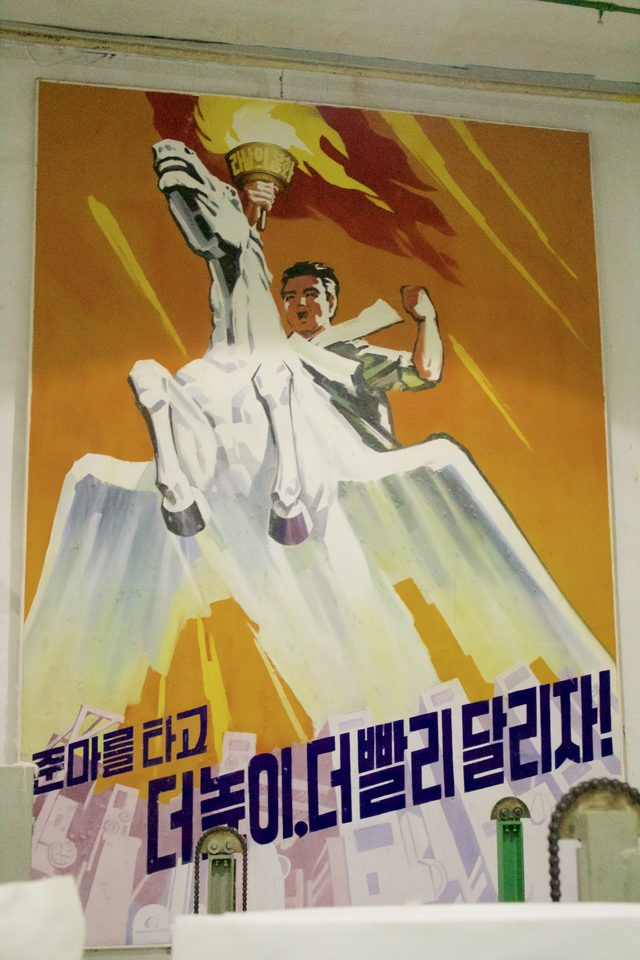 "Ride the Chollima, run higher and faster!": factory wall poster, North Korea (photographed 2016)