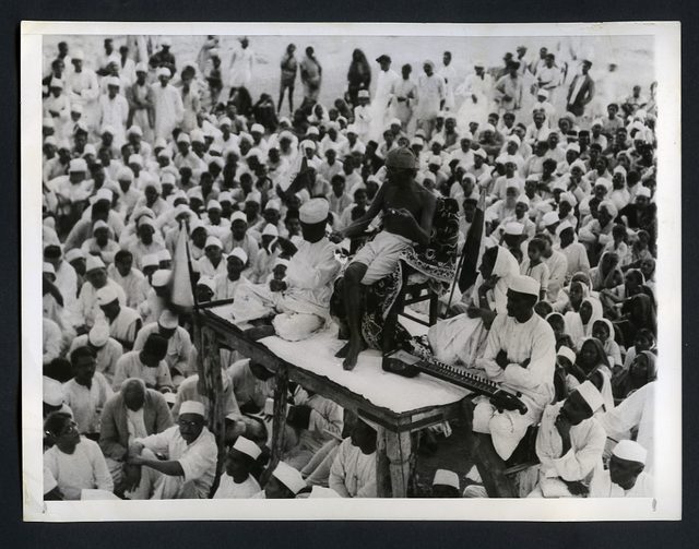 Gandhi spins while addressing a crowd (1930)