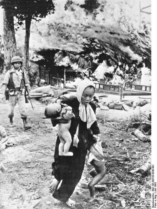 Zentralbild "Terror in Südvietnam": woman and children before a burning house
