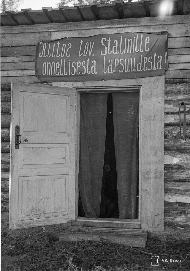 'Kiitos tov. Stalinille onnellisesta lapsuudesta!' (Thanks to Comrade Stalin for a happy childhood): banner over a hut door, Vidlitsa