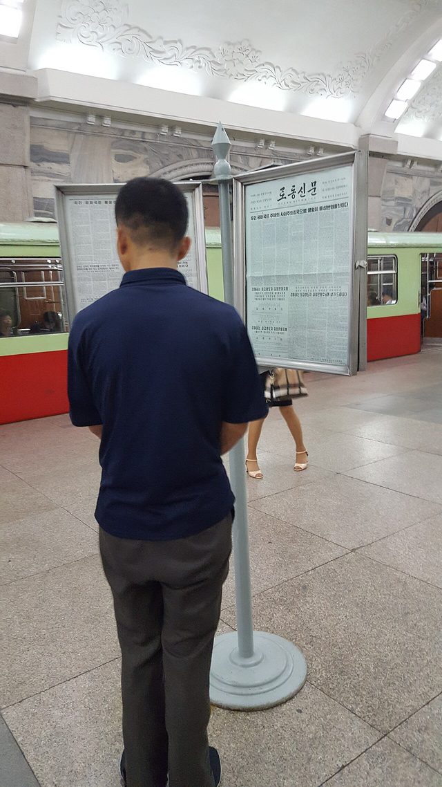Passenger reading Rodong Sinmun, Puhung Station, Pyongyang Metro (photographed 2017)