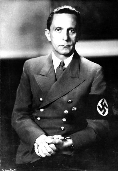 Joseph Goebbels seated in a double-breasted uniform jacket with a swastika armband, studio portrait