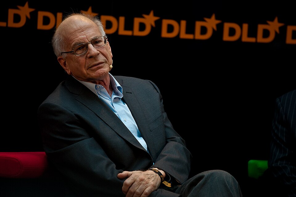 Daniel Kahneman seated on a stage in front of a DLD conference backdrop
