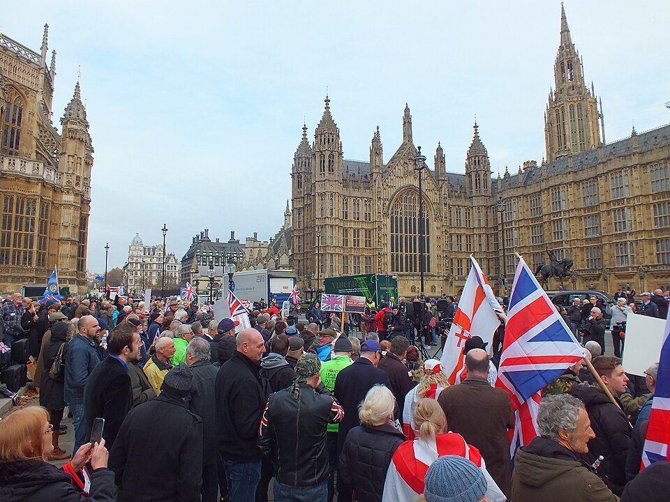 Crowd holding Union and St George flags at a pro-Brexit rally outside the Houses of Parliament