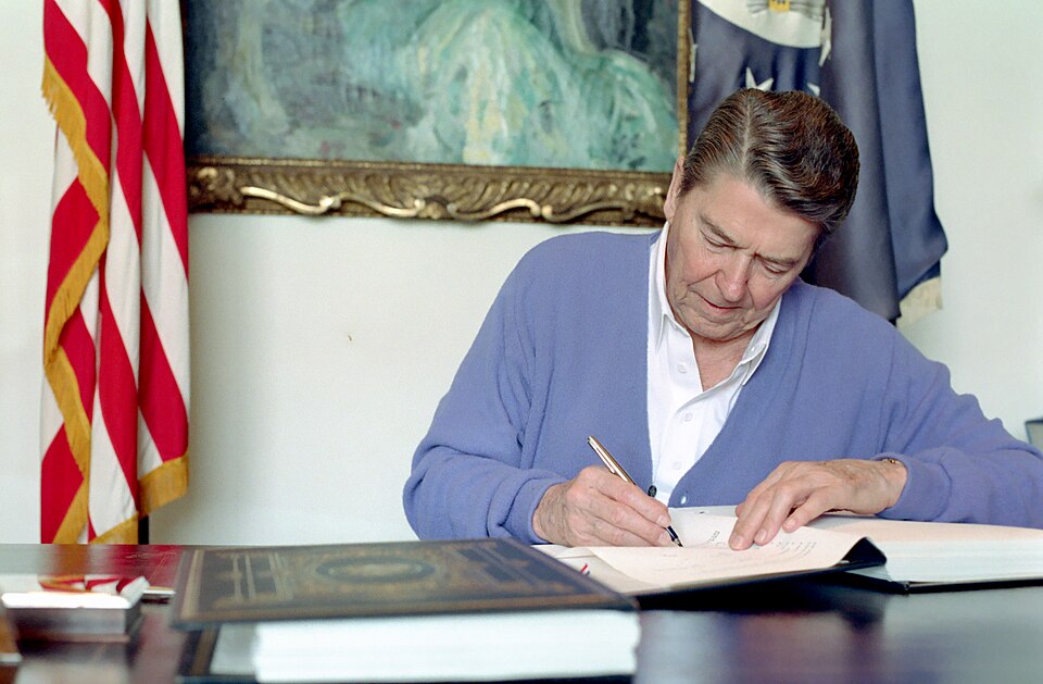 President Reagan signing the United States-Canada Free Trade Agreement at a desk