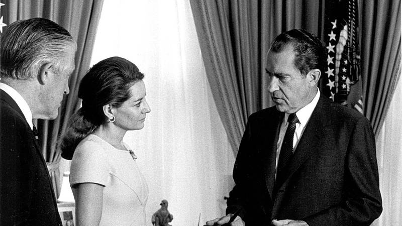 President Nixon in the Oval Office with George Romney and Barbara Walters, with stacks of telegrams on the desk