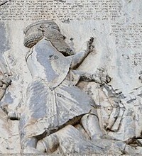 Darius I in the Behistun relief, in profile with a tall crown, raising a hand