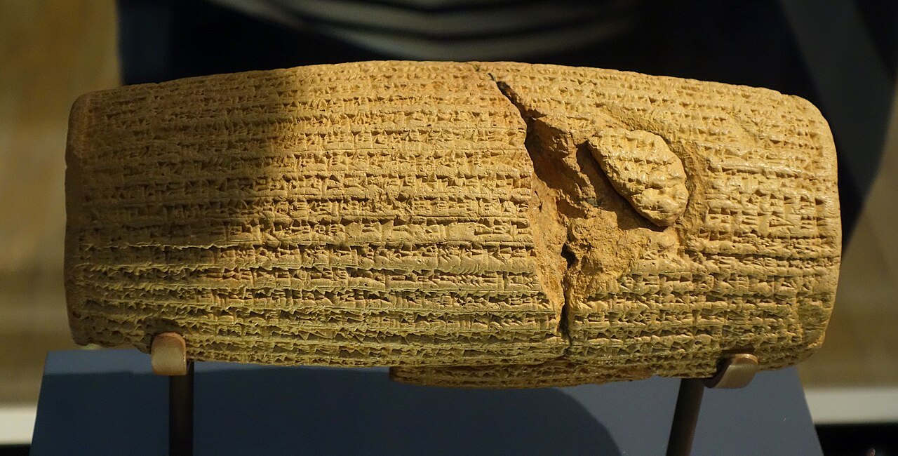 The Cyrus Cylinder, a broken barrel of baked clay covered in lines of cuneiform, on a display stand