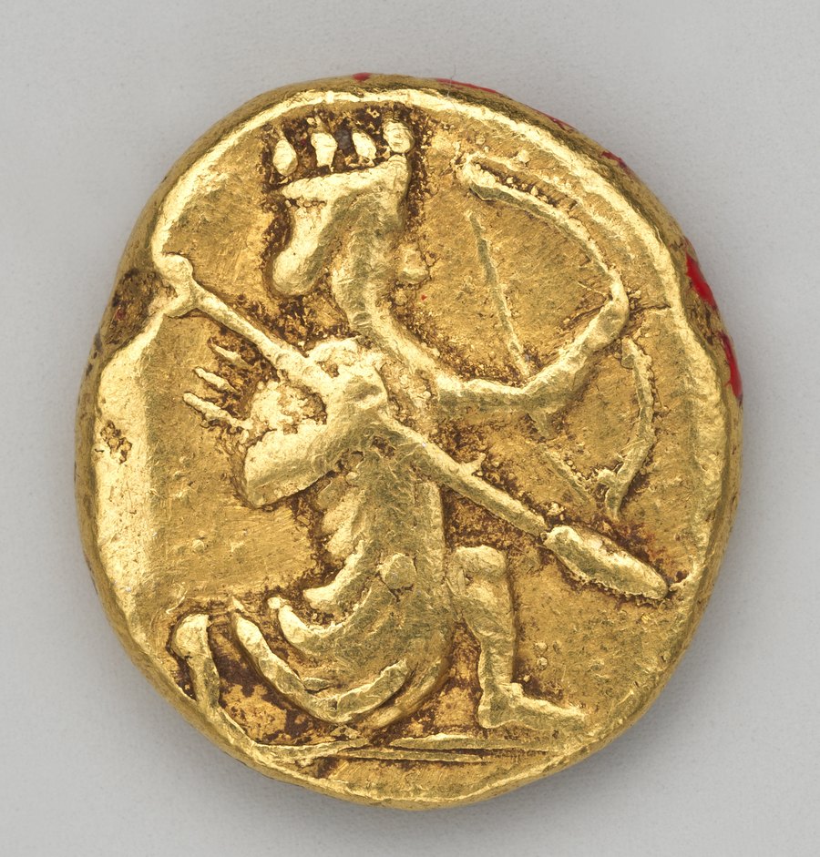 A small gold coin showing a crowned king kneeling and drawing a bow, with a spear held in the other hand