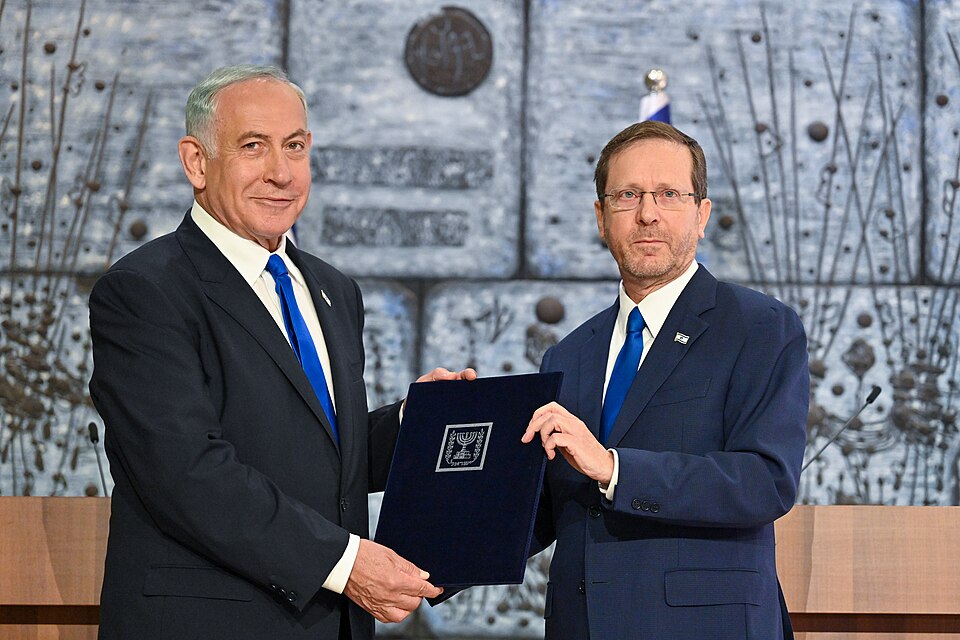 Benjamin Netanyahu, left, and President Isaac Herzog, right, hold a dark folder bearing the Israeli state emblem between them