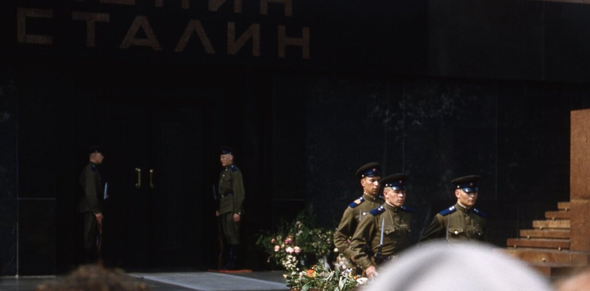 Part of the front of the Mausoleum on Red Square: the end of the word LENIN and the name STALIN in gilt letters above the doors, with guards at the entrance and a wreath