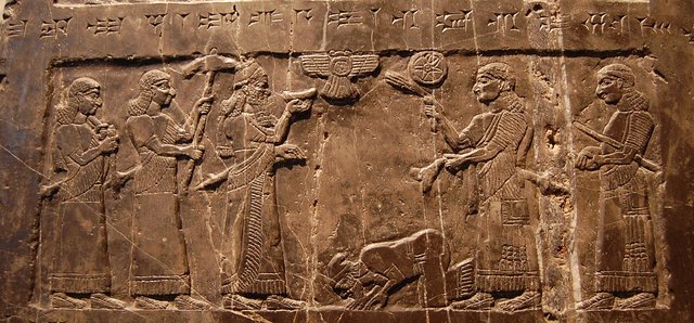 One panel of the Black Obelisk of Shalmaneser III: officials stand at left and right under a winged disk and a kneeling figure, with a line of cuneiform above