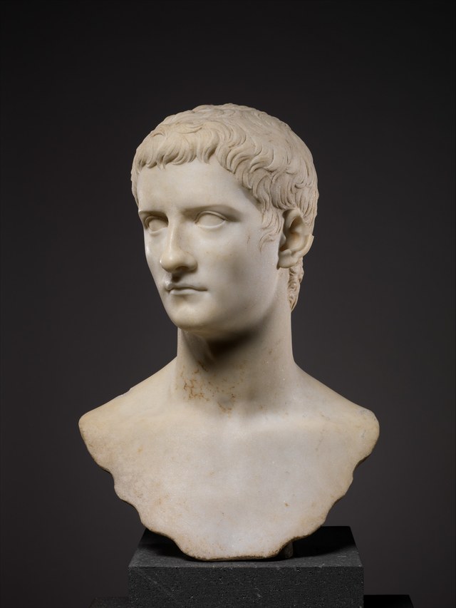 Marble portrait bust of Gaius (Caligula), a young man with short combed hair, on a dark ground