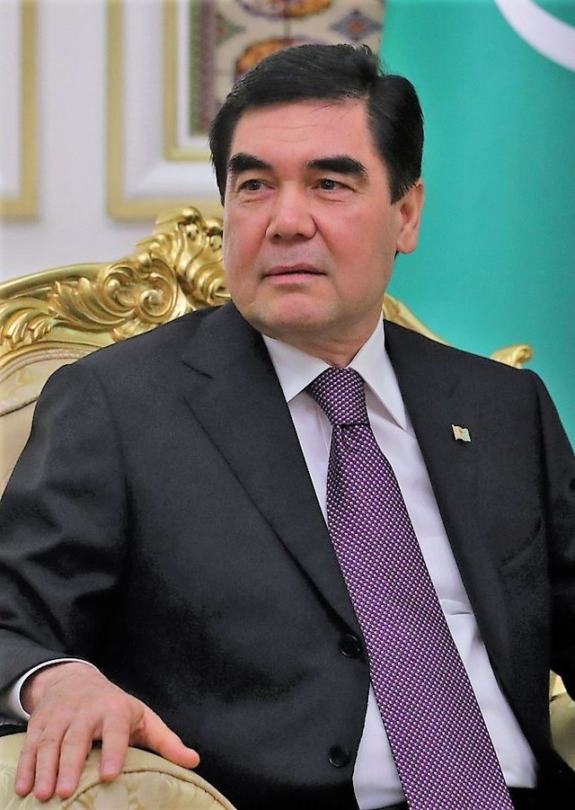 Gurbanguly Berdimuhamedov seated in a gilded chair beside the Turkmen flag, in 2017