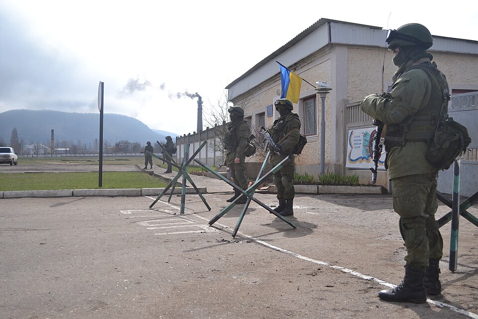 Armed men in uniform without national insignia at a gate of the Ukrainian military base at Perevalne, Crimea, 9 March 2014