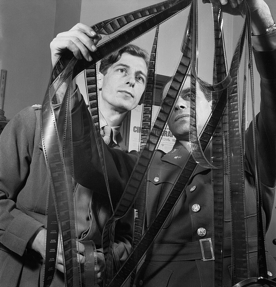 Frank Capra in Army uniform and Roy Boulting of the British Army Film Unit examining strips of film, February 1944