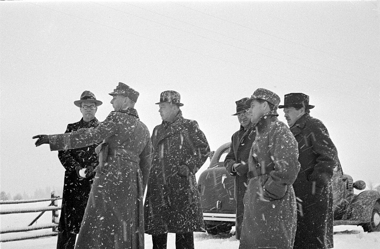 Group of men in overcoats at Mainila in falling snow, 29 November 1939