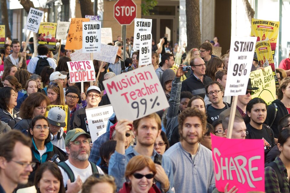 Protesters holding "Stand with the 99%" and other signs at Occupy Oakland